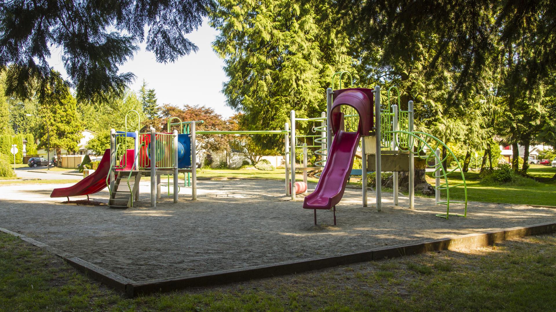 Large trees shade the majority of a playground.